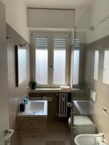 ein Badezimmer mit zwei Waschbecken, einem WC und zwei Fenstern in der Unterkunft Bright Place Navigli in Mailand