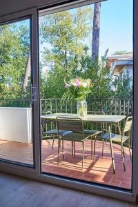 einen Tisch mit Stühlen und eine Vase mit Blumen auf dem Balkon in der Unterkunft Magnifique Appartement Design Parking Chiberta in Anglet