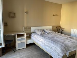 ein kleines Schlafzimmer mit einem Bett und einem Schreibtisch in der Unterkunft Appartement 42 m2 à Vittel proche Thermes-SPA in Vittel
