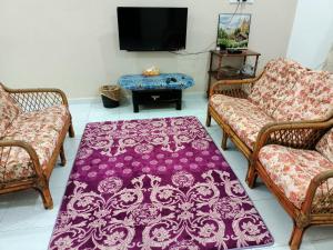 a living room with two chairs and a purple rug at Ummi's Homestay Kuala Besut in Kampong Baru