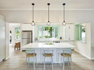 a kitchen with a white island and two stools at Southwinds Beach House in Saint Peter