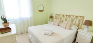 een witte slaapkamer met een wit bed en een spiegel bij Apartamento Mediterráneo by DENIA COSTA in Denia