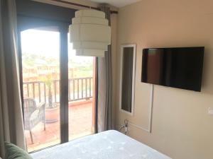 sypialnia z telewizorem z płaskim ekranem i balkonem w obiekcie Duplex Penthouse in Estepona- Mountain and Sea views w mieście Estepona