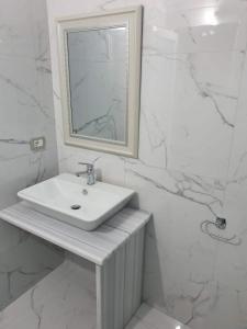 a white bathroom with a sink and a mirror at Victoria Studio Himara in Himare +37 photos