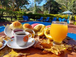 a table with a cup of orange juice and some food at Pousada Recanto da Montanha in Visconde De Maua