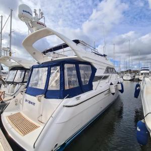 a white boat docked at a dock in the water at Mad Moment-Two Bedroom Luxury Motor Boat In Lymington in Lymington