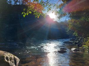 a river with the sun reflecting on the water at Pousada Recanto da Montanha in Visconde De Maua