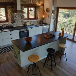 una cocina con una gran isla con taburetes. en CASAS DA MORGADINHA - Casas de Férias e Turismo Rural, en Celorico de Basto