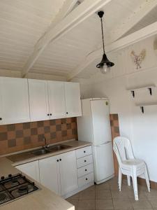 uma cozinha com armários brancos e um frigorífico branco em Soggiorno paradisiaco in bungalow sulla spiaggia em Crotone