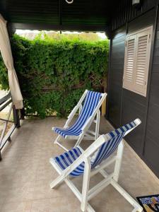 two lawn chairs sitting on a patio with a hedge at Soggiorno paradisiaco in bungalow sulla spiaggia in Crotone