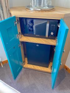 ein blauer Schrank mit einer Mikrowelle darüber in der Unterkunft An-Airidh Bed & Breakfast Portree in Portree