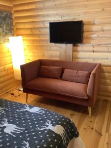 a living room with a brown couch and a flat screen tv at Chalet Les Sorbiers in Égat