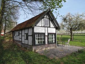 a small black and white building in a field at Vakantiewoningen 'Hoeve de Witte Olifant' in Noorbeek