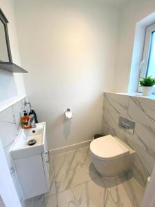 a white bathroom with a toilet and a sink at NEW Beautiful Large 3 bedroom House - 5 Minutes to the nearest Beach! - Great Location - Garden - Parking - Fast WiFi - Smart TV - Newly decorated - sleeps up to 7! Close to Poole & Bournemouth & Sandbanks in Lytchett Minster