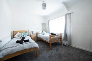 a bedroom with two beds and a window at Swansea Cosy Stay in Swansea