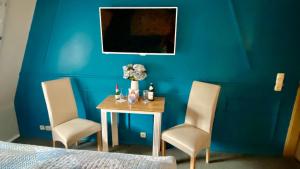 ein Schlafzimmer mit einem Tisch, 2 Stühlen und einer blauen Wand in der Unterkunft Froeschlein 2 - no Gitters & craftsman in Ilmenau