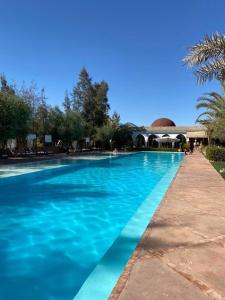a large blue swimming pool with a building in the background at Manzil La Tortue in Douar Caïd Layadi