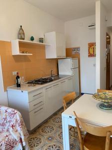 a kitchen with white cabinets and a table and a table and a dining room at Appartamento Mare Blu in Sciacca