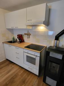 a kitchen with white cabinets and a sink and a stove at Ferienwohnung Sonnenhaus in Wonsees +4 photos