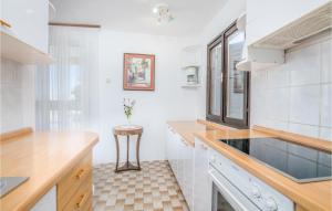 kuchnia z białymi ścianami, umywalką i stołem w obiekcie 1 Bedroom Nice Apartment In Stara Baska w mieście Stara Baška