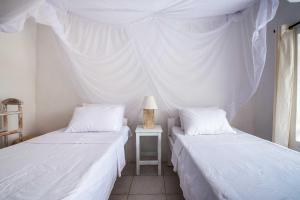 een slaapkamer met 2 bedden en een tafel met een lamp bij Flamboyant Diani Beach in Diani Beach