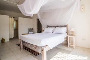 
a bed with a white bedspread and pillows at Flamboyant Bed and Breakfast in Diani Beach
