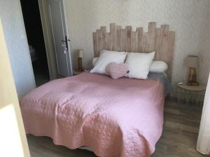 un letto con coperta rosa e cuscini bianchi di Le Clos Mesnil a Le Mesnil-Réaume