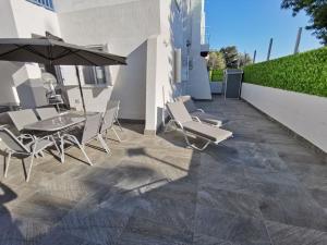 een patio met een tafel en stoelen en een parasol bij Paphos Gardens Apartment in Paphos City