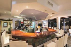 a large bar in a room with white chairs at Paphos Gardens Apartment in Paphos City