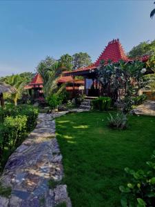 a pathway leading to a house with a grass yard at Mirabelle Joglo Village in Karimunjawa