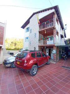czerwony samochód zaparkowany przed budynkiem w obiekcie Portal de la Cascada - Mongui w mieście Monguí