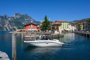 a white boat in the water next to a town at Hotel Benaco in Nago-Torbole