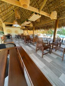 ein Restaurant mit Holzstühlen, Tischen und einem Dach in der Unterkunft Hotel Sand Bay in Punta Rucia