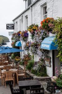 a restaurant with tables and umbrellas in front of a building at Port Gaverne Hotel in Port Isaac