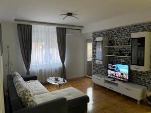 ein Wohnzimmer mit einem Sofa und einem Flachbild-TV in der Unterkunft Apartman MDB in Subotica