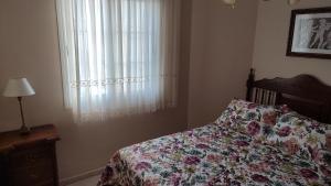 - une chambre avec un lit doté d'un couvre-lit floral et d'une fenêtre dans l'établissement Apartamento Paseo Marítimo, Centro Torre del Mar, à Torre del Mar