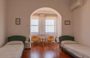 Dos camas en una habitación con ventana y mesa. en Terrazza Ionica - Apartment Sea View Wifi, en Siracusa