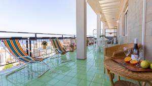Un balcón con sillas y mesas en un edificio. en Terrazza Ionica - Apartment Sea View Wifi, en Siracusa