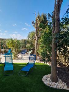 zwei blaue Gartenstühle neben einem Baum in der Unterkunft Cap Capistol Golf, appartement 2 chambres in Cap d'Agde