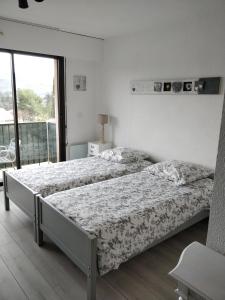 een slaapkamer met 2 bedden en een groot raam bij Studio Lou Cigaloun in Gréoux-les-Bains