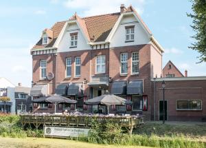 um edifício com mesas e guarda-chuvas à sua frente em Gasterij Posthuys em Leerdam