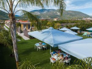 a group of people sitting at tables under a blue umbrella at Desa Green Homes in Ancient Epidavros