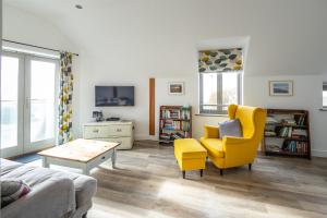 a living room with a yellow chair and a table at Coastguard Lookout in Weymouth