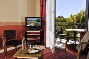 a living room with a television and a balcony at Logis Hotel Le Sablier du Temps in Argentat