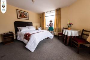 ein Hotelzimmer mit einem Bett und einer Frau aus dem Fenster in der Unterkunft Hotel Nativa in Chivay