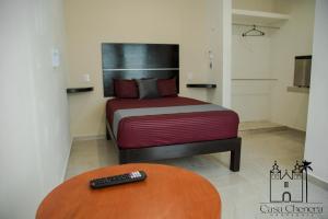 a bedroom with a bed with a remote control on a table at Casa Chenera in Campeche