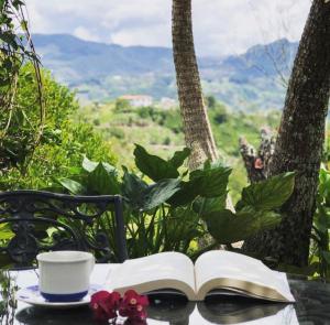 un libro abierto sentado en una mesa con una taza de café y un aucer en Casa Santamaria Hotel Campestre, en Jericó