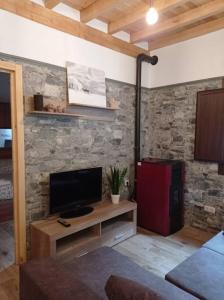 - un salon avec une télévision et un mur en pierre dans l'établissement Casa Rural Güilones, Parque Natural de Ponga, à Sobrefoz