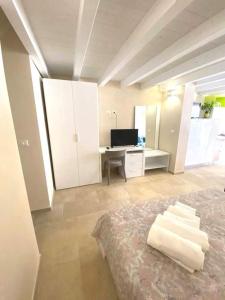 une chambre avec un lit et un bureau avec une télévision dans l'établissement La maison del corso, à San Foca