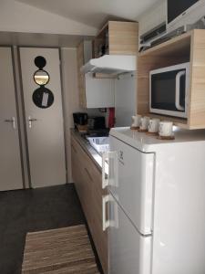 W kuchni znajduje się biała lodówka i kuchenka mikrofalowa. w obiekcie Mobile-Home 6 personnes Cap Ferret w mieście Claouey